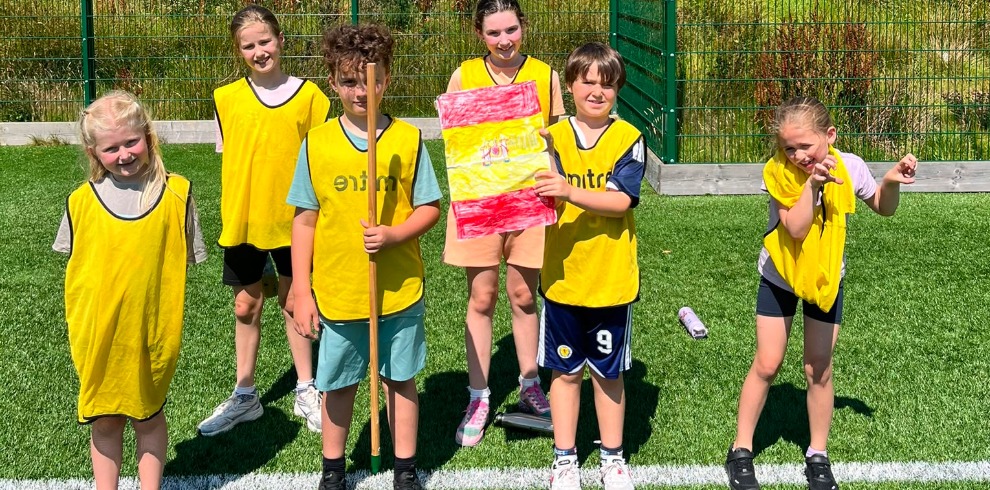 Children standing in a field posing for a photograph with a flag.