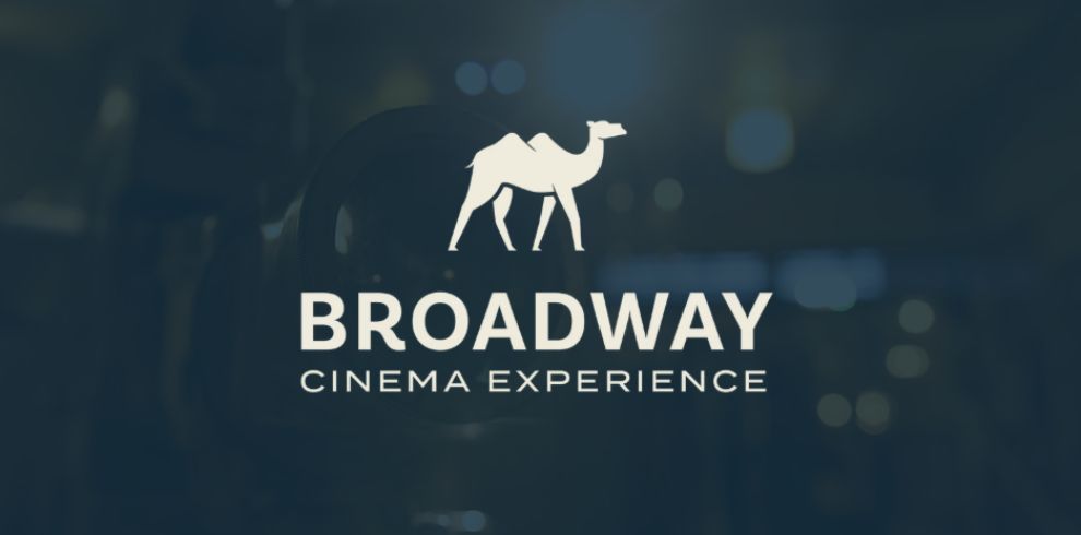 Promotional banner for The Broadway Cinema Experience featuring a white camel logo above the words “BROADWAY CINEMA EXPERIENCE” in bold white text. The logo and text are centred on a dark blue background with soft, out-of-focus lights, creating a cinematic atmosphere.