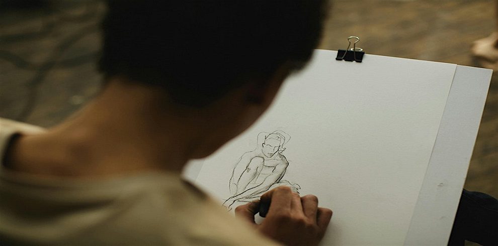 A person sitting drawing on a piece of paper.