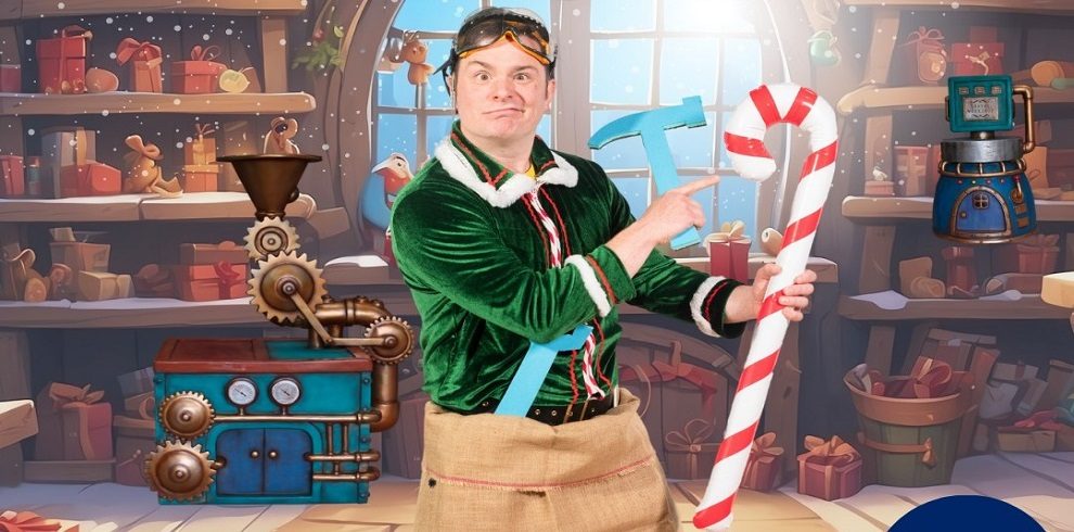 Ivor the Elf holds a candy cane with a mischievous grin, standing in Santa's workshop. The background features colourful toys, festive decorations, and workbenches filled with Christmas gifts.