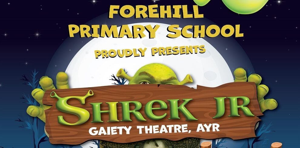 A picture of Shrek, the green ogre from the animated movie, peeking out from behind a sign that reads "Shrek JR Gaiety Theatre." Shrek's large ears and broad smile are visible as he leans around the edge of the sign, adding a playful touch to the scene. The sign is prominently displayed, indicating an event or performance related to Shrek JR at the Gaiety Theatre.