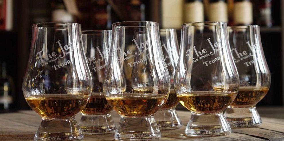 An image of 6 whiskey glasses placed on a table.