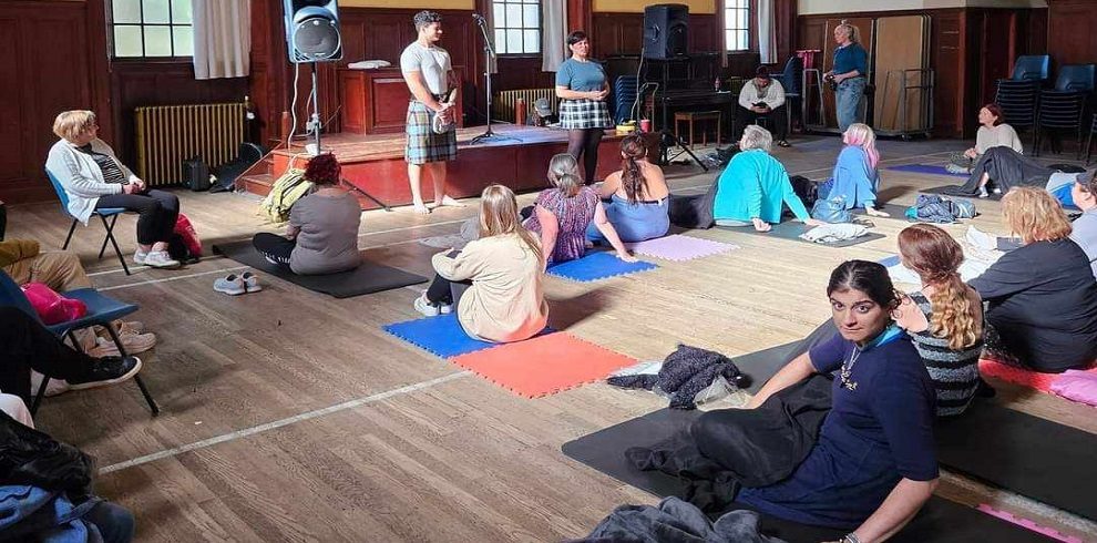 A hall full of people relaxing and listening to an instructor.