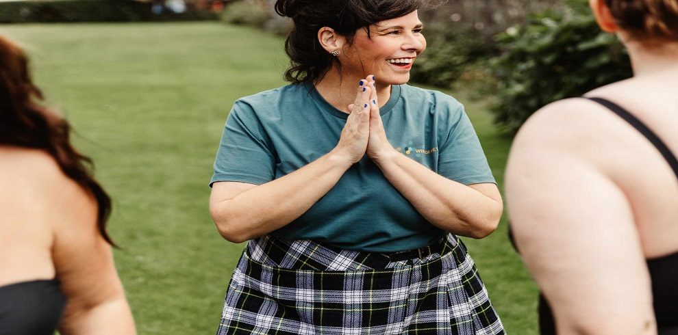 A lady standing outside in a garden looking happy and relaxed.