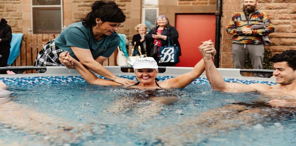 A lady in a pool relaxing and recieiving a massage from another lady.