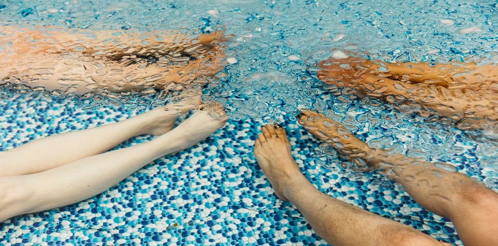 picture of four sets of legs under water in a pool.